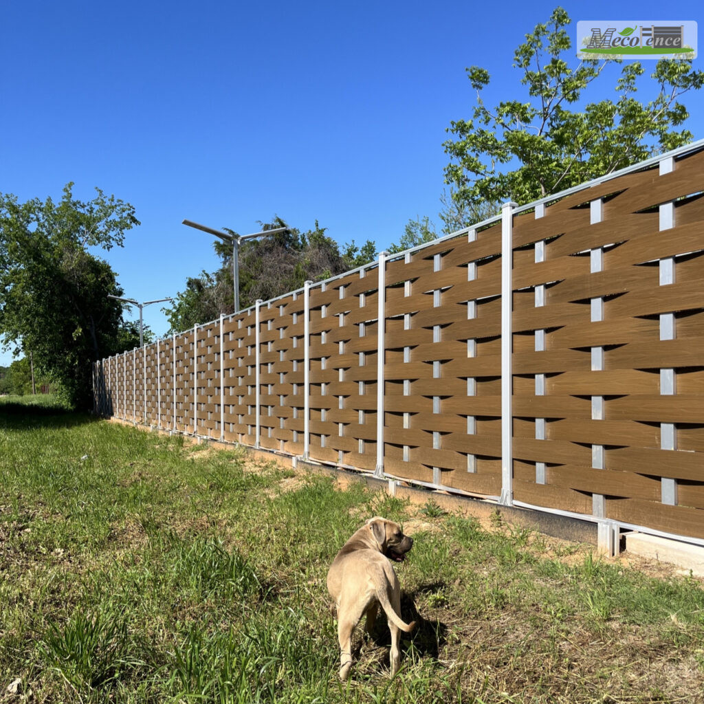 brown woven composite fence with silver posts under a clear blue sky.