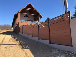 Brown Mecofence WPC privacy fence with a stepped installation on a concrete retaining wall in Austin, Texas, providing a durable and modern boundary solution for sloped residential properties.