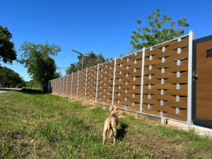 Light brown Mecofence woven WPC boundary fence paired with a solid gate at a roadside property in Lyon, France, providing a cohesive and durable perimeter system for global wholesalers.