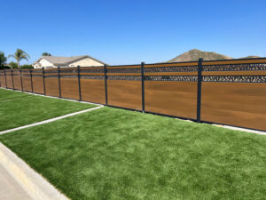 Close-up view of the clean connection between a dark grey WPC composite fence panel and its matching aluminum post with a top cap, installed in a modern French residential garden setting.
