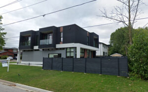 Dark grey WPC composite fence panel being installed with an aluminum post and a hand, creating a clean boundary in a standard Japan suburban backyard garden with a lawn and paving.