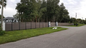 Expansive brown Mecofence WPC semi-privacy fence with a driveway gate, delivering durable and scalable boundary solutions for overseas commercial and residential constructors.