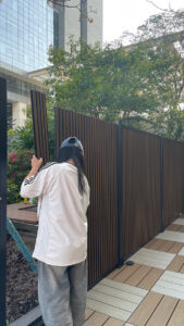 Installer fitting a Mecofence dual tone fluted WPC composite fence panel, demonstrating quick assembly and modern design for global constructors.