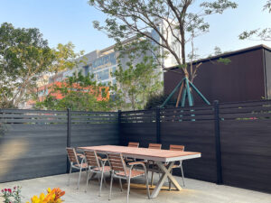 Dark grey Mecofence WPC semi-privacy fence enclosing an urban patio, offering durable and modern boundary solutions for commercial constructors globally.