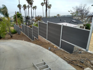 Grey Mecofence WPC stepped privacy fence installed on a steep slope, providing adaptable hillside boundary solutions for overseas residential constructors.