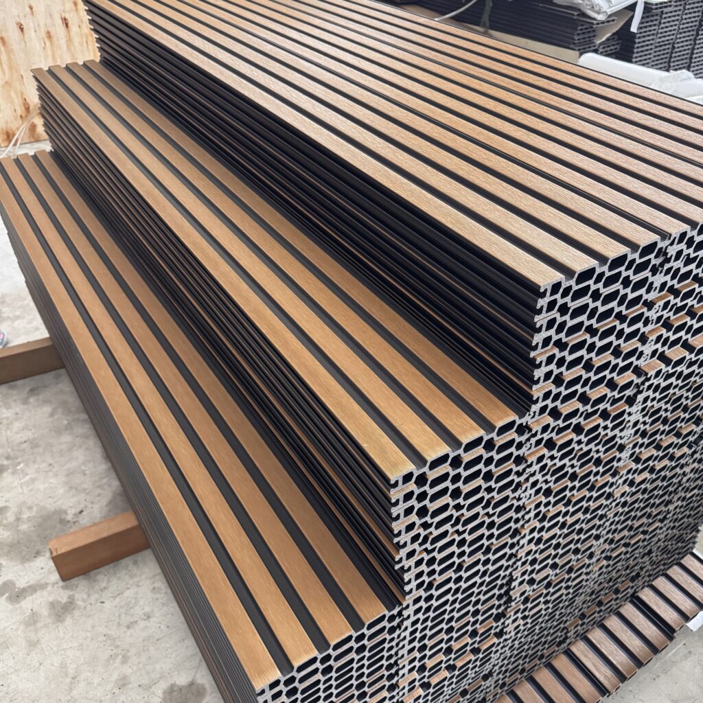 Close-up of **stacked inventory** of dual-tone composite slat fence boards, showing the extruded profile and **high volume** available for immediate **wholesale order fulfillment**.