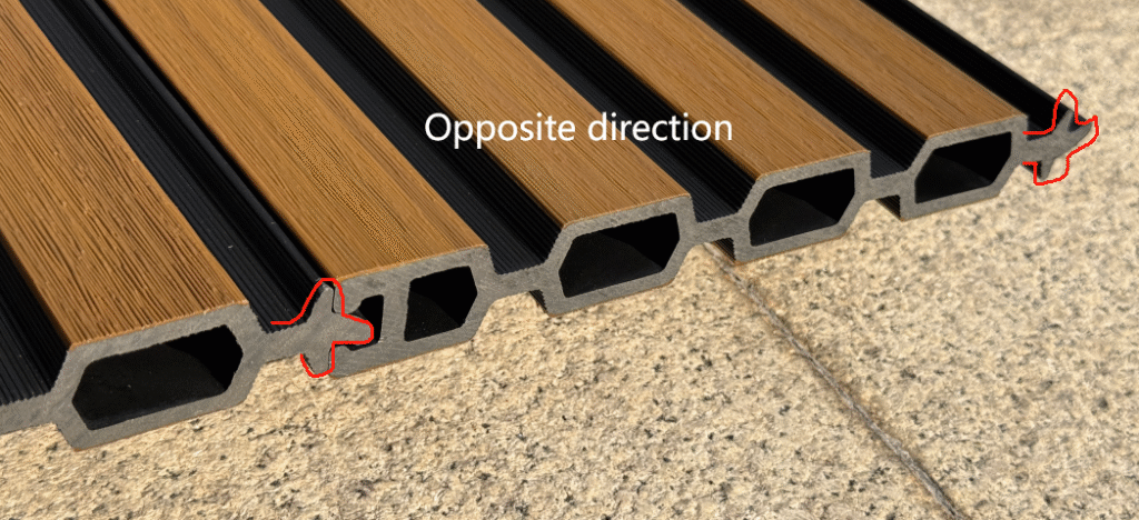 Close-up cross-section of Mecofence fluted composite fence panel, displaying the hollow core interior and the tongue-and-groove interlocking edges designed for seamless horizontal stacking.