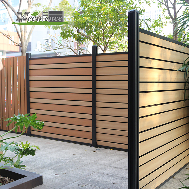 Installed ASA co-extrusion PVC fence with horizontal wood-look boards, dark aluminium posts and a privacy boundary in an urban garden courtyard