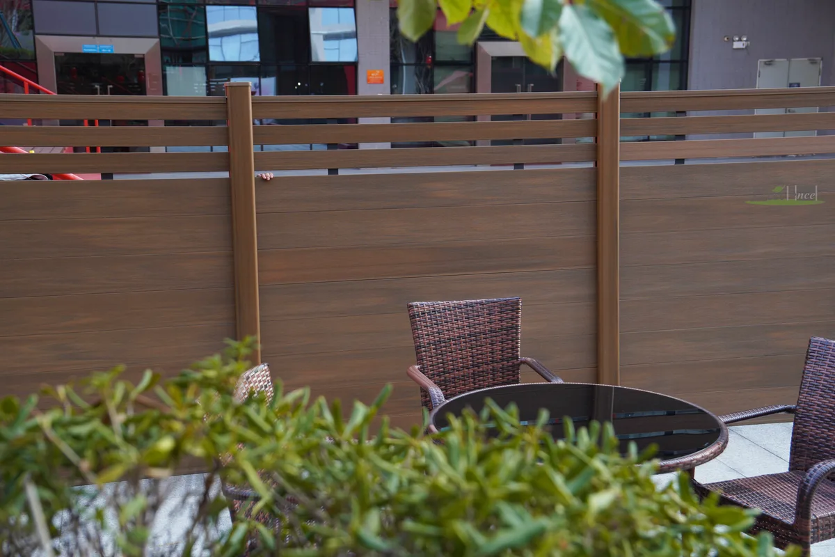 Coffee mid-trellis composite kit fence with colour-matched posts beside outdoor cafe seating