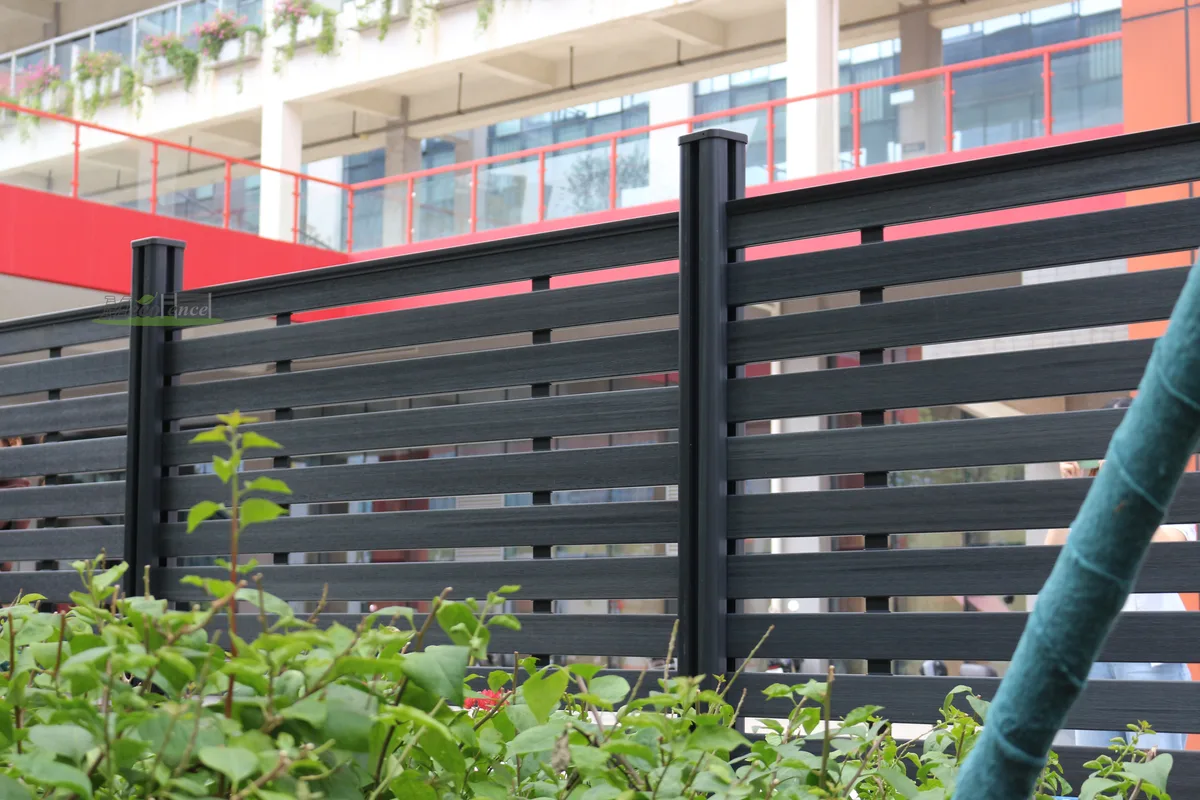 Dark grey full-trellis composite kit fence with black posts along a planted street edge