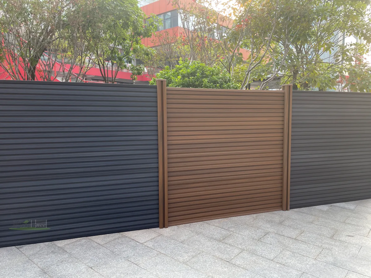 Privacy composite kit fence in fluted design run mixing dark grey and teak panels with matching posts
