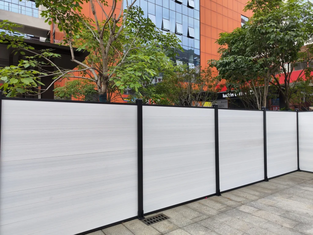 White composite privacy fence with black posts along a planted courtyard