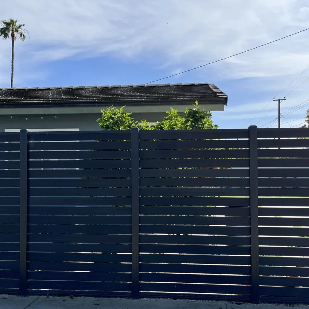 Dark grey full-trellis composite fence run with aluminium posts along a residential street