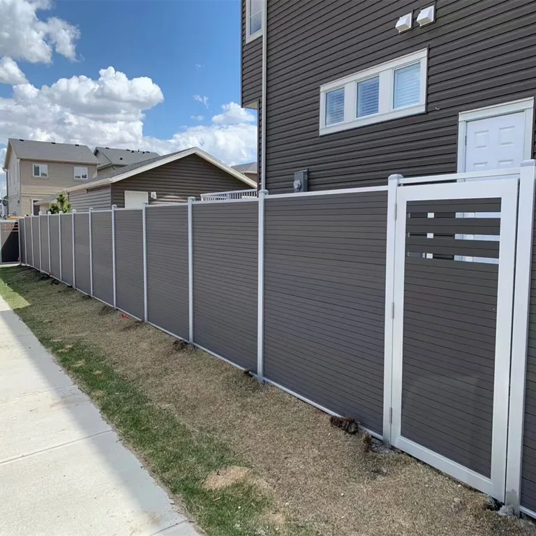 Single-leaf composite gate with slotted top section in a dark grey fence line