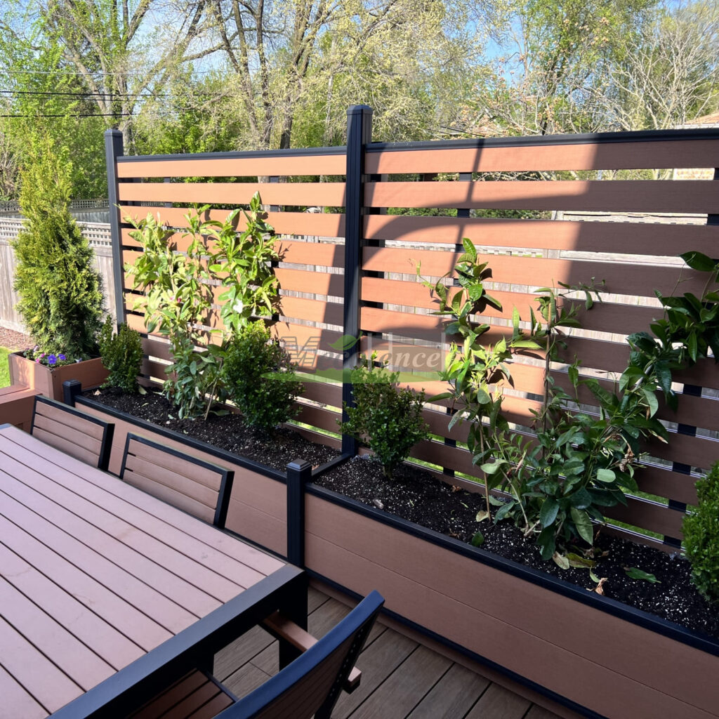 Modern brown composite fence with integrated flower box, featuring horizontal slat design and lush greenery for outdoor privacy.