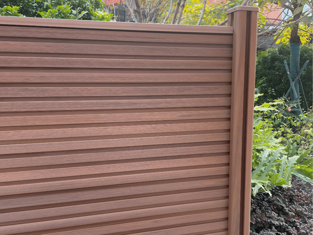 MecoFence Fluted Composite Fence Panel in premium Teak finish. Modern 3D ribbed WPC board design for colorful, architectural fencing.