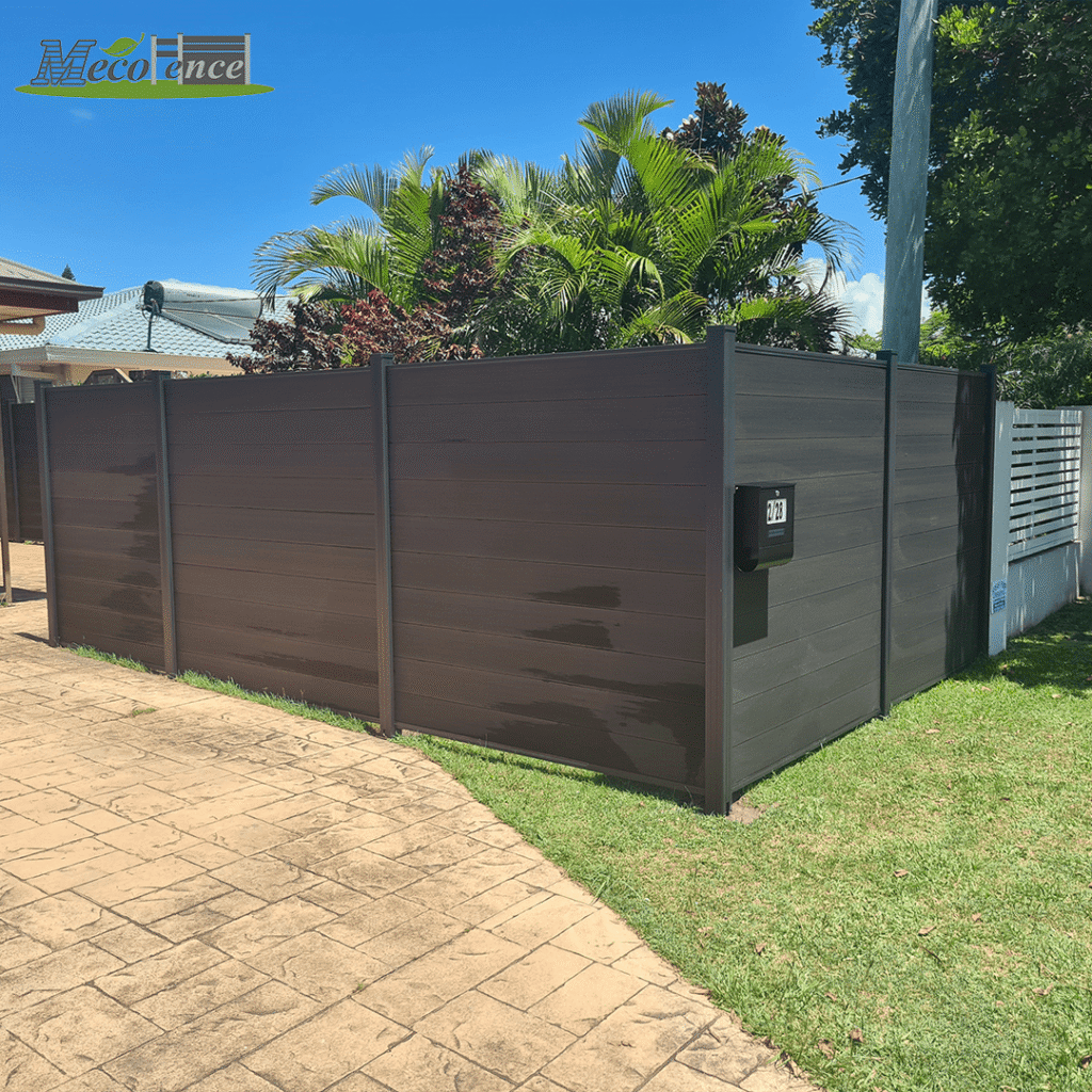 Installed MecoFence 6ft black composite privacy fence in a residential garden setting with tropical plants