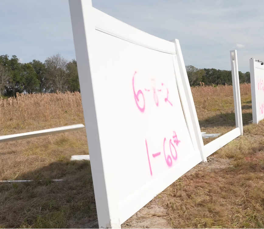 Field test showing a standard vinyl fence post kinking at the base under 60-75 mph simulated hurricane winds generated by an airboat."
