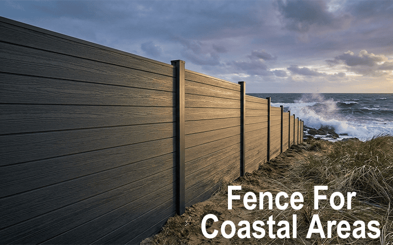 Dark charcoal composite privacy fence standing firm along a coastal shoreline with crashing ocean waves and sea spray in the background