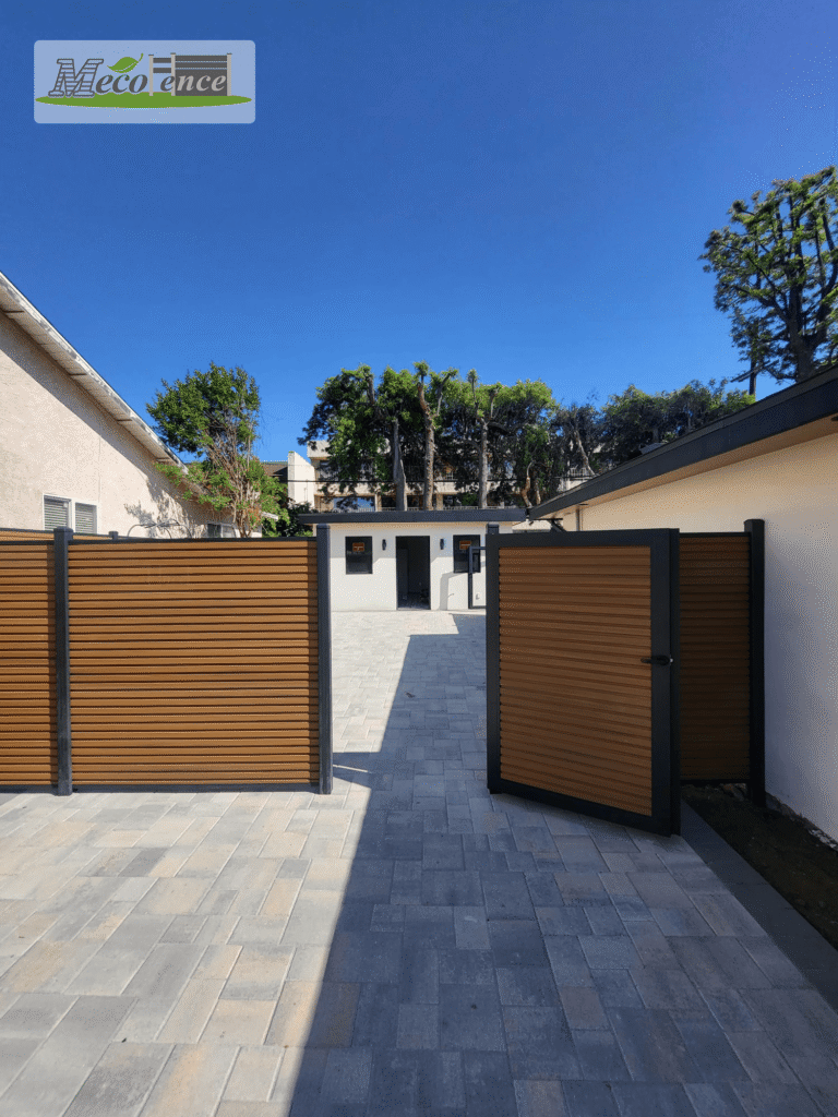 Teak fluted composite fence courtyard with matching pedestrian gate, paver hardscape