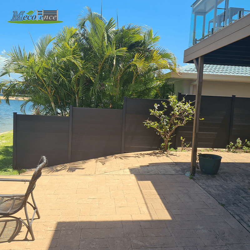 Completed MecoFence dark composite privacy fence on a waterfront Gold Coast property in Australia under tropical sun