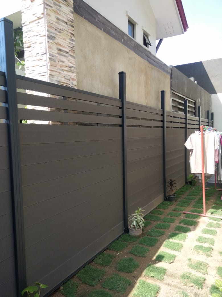 MecoFence composite fence installed in the Philippines — walnut privacy panels with a slat top and black aluminum posts, 2021