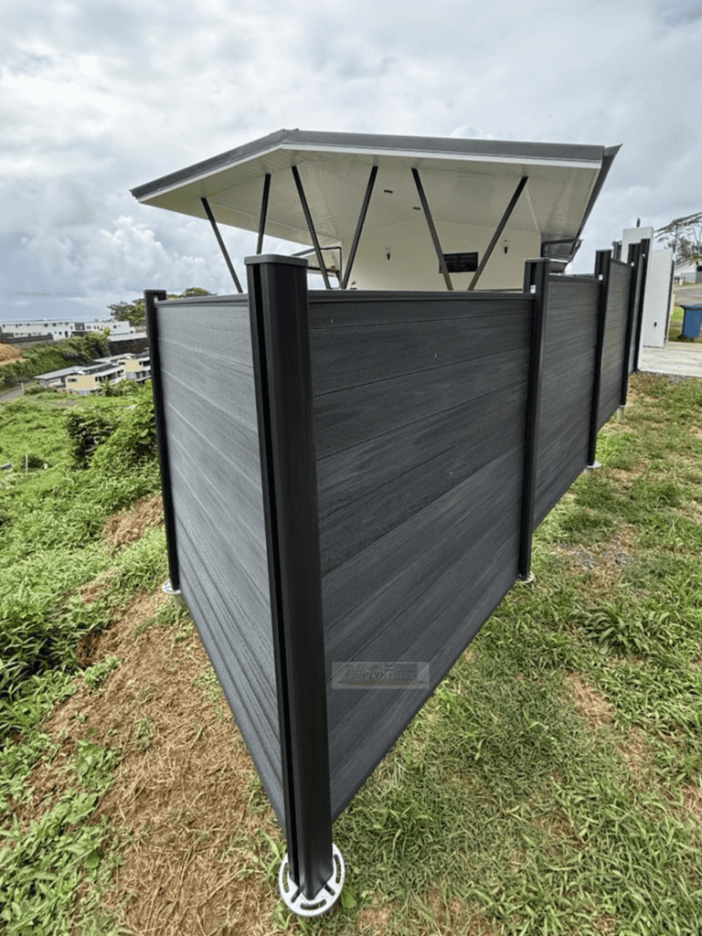 Dark Grey WPC fence panels stepping up a grassy hillside slope in French Polynesia