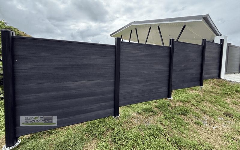 Dark Grey WPC fence panels stepping up a grassy hillside slope in French Polynesia