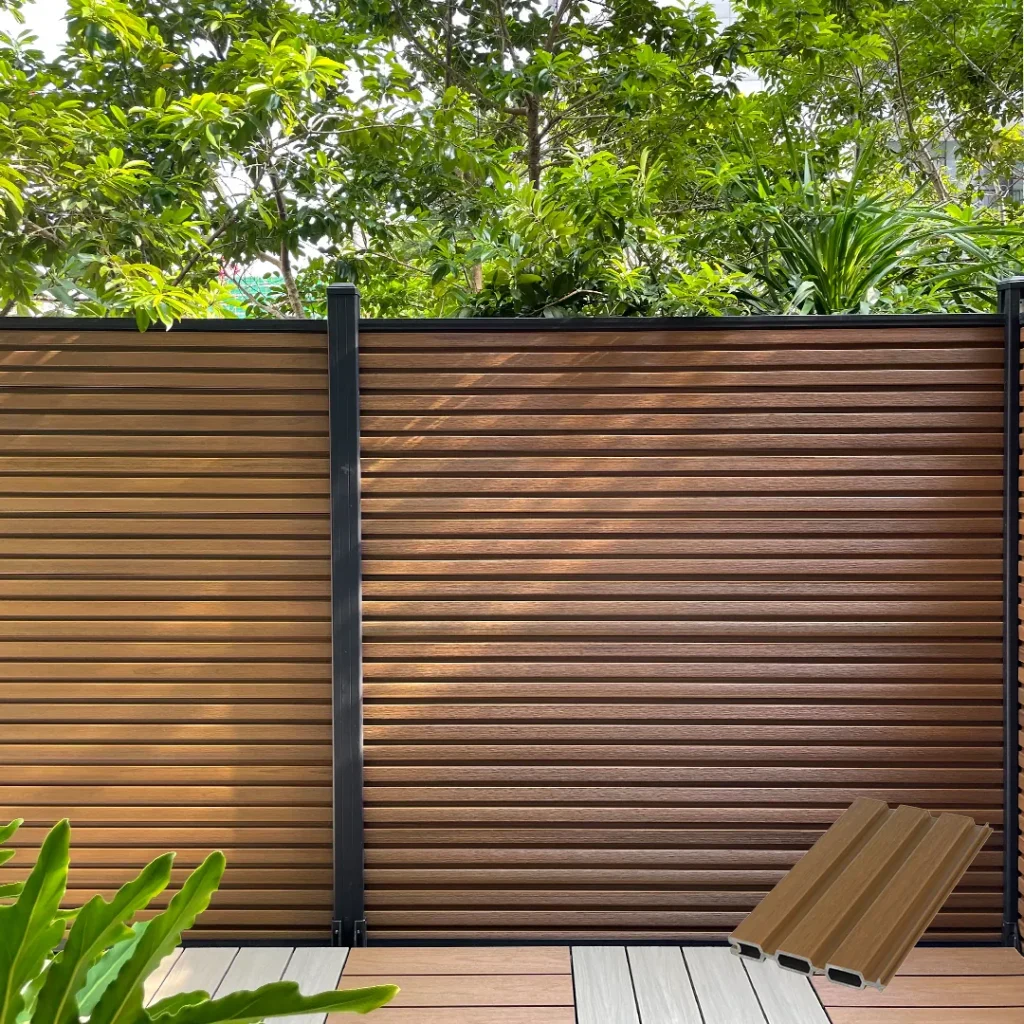Teak fluted composite fence with horizontal slats and black aluminum posts in a garden
