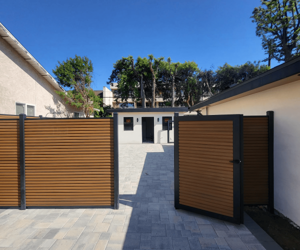 Teak fluted composite fence courtyard with matching pedestrian gate, paver hardscape