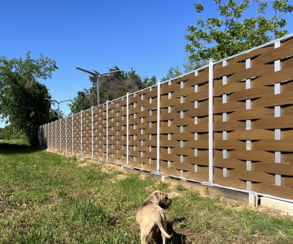 brown woven composite fence with silver posts under a clear blue sky.